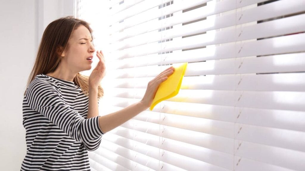 женщина чихает во время уборки пыли