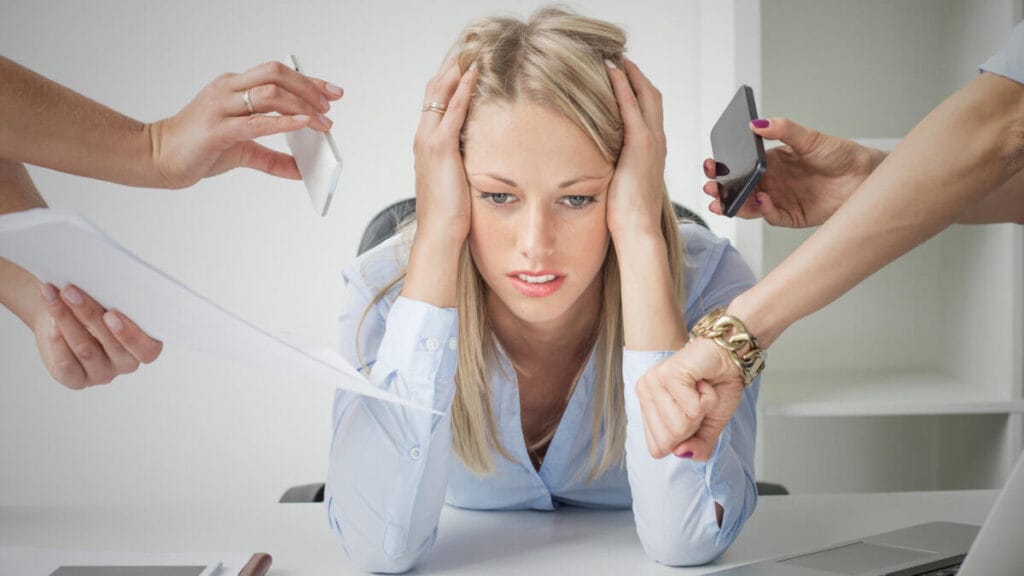 A woman sits in an office with pronounced fatigue and anxiety.